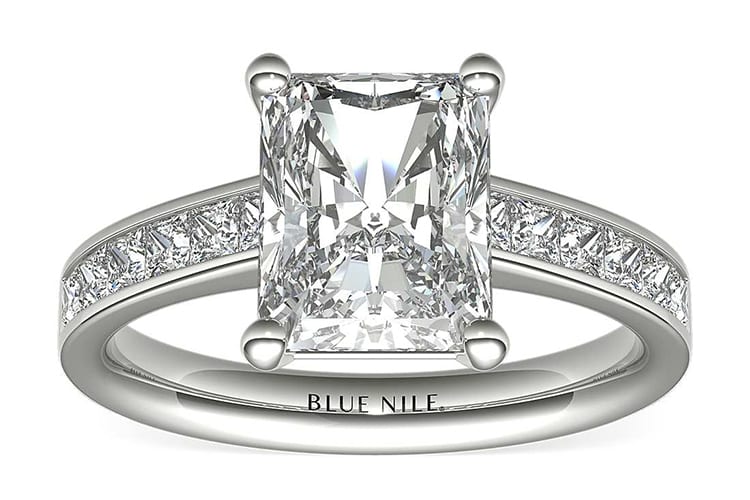 Diamond engagement ring showcasing twelve princess-cut diamonds channel-set in 14k white gold and accenting a center diamond. (Photo by Blue Nile).