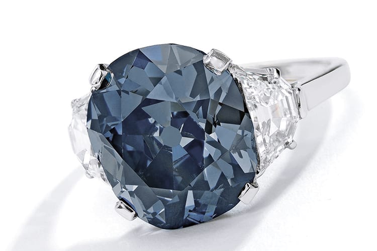 ‘The Indian Blue,’ an exceptional fancy deep grayish blue diamond and diamond ring. Centering a cushion-cut fancy deep grayish blue diamond weighing 7.55 carats. Natural color, SI2 clarity. Estimated to be $6 million to $8 million. (Photo Courtesy of Sotheby’s)