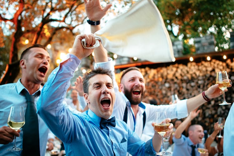 Three men celebrate at the wedding reception.