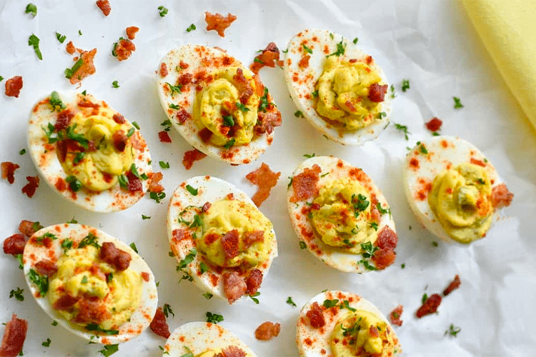 Plate of deviled eggs topped with bacon bits