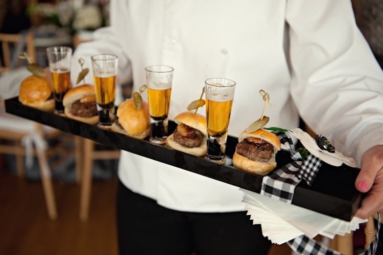 Mini cheeseburger sliders presented on tray with mini beers