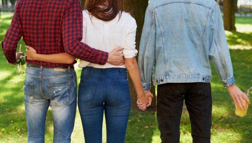 A couple arm in arm, while the woman holds hands with another man